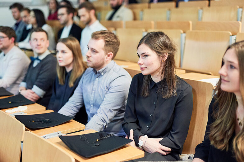 Personen sitzen in einem Hörsaal auf der Werkschau/der Abschlussfeier am Fachbereich Architektur