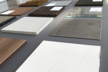 Various material samples are presented on a table in the foyer of the Faculty of Architecture. In the foreground are samples of granite, stone, glass and wood.