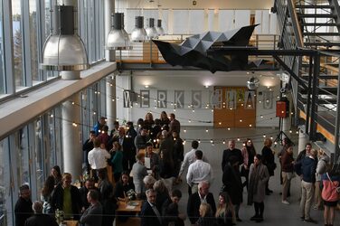 View of the faculty foyer filled with guests standing at bar tables.