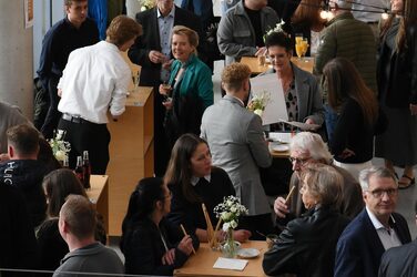 View of the faculty foyer filled with guests standing at bar tables.