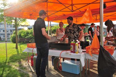 Unter orangefarbenen Pavillons versorgt die Fachschaft die Gäste mit Getränken.