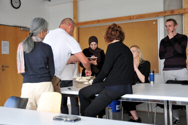 Studierende sitzen mit den Lehrenden am Tisch und besprechen ihr Arbeitsmodell.