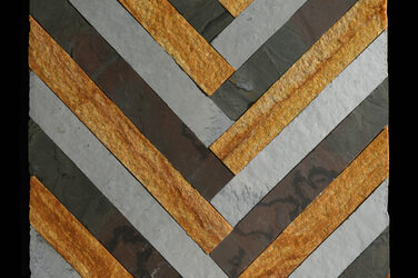 Three different natural stones cut into strips and arranged in a herringbone pattern on a slab