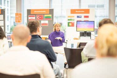 Prof. Ulrike Brückner berichtet in ihrem Info-Talk von ihrem Auslandsworkshop in Kenia. Das Publikum hört gespannt zu.In her info talk, Prof Ulrike Brückner talks about her workshop abroad in Kenya. The audience listens intently.