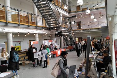 Übersicht über das Foyer des Fachbereichs Architekur der Fachhochschule Dortmund mit Ausstellerständen des international Day. Studierende informieren sich an den Ständen zu Fragen rund um den Auslandsaufenthalt. Overview of the foyer of the Faculty of Architecture at Dortmund University of Applied Sciences and Arts with exhibitor stands at the International Day. Students inform themselves about questions concerning their stay abroad.