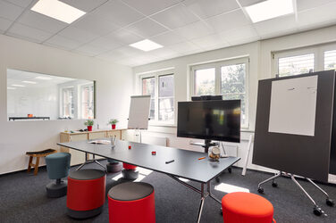 Room shot with a conference table, flipchart, digital board and note board.