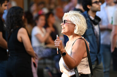 Eine Person mit Sonnenbrille wendet sich lachend nach rechts, der Sonne entgegen.