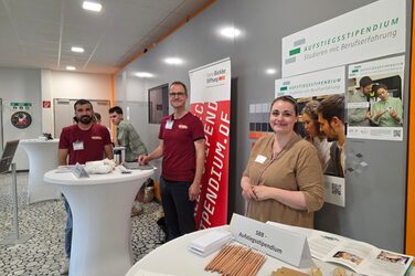 Mehrere Personen stehen an Tischen in einem Foyer.
