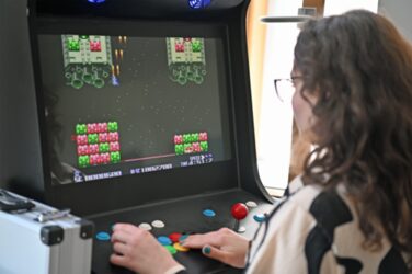 Einer Person spielt an einem selbst gebautem Spielautomaten der FH Dortmund ein Computerspiel.