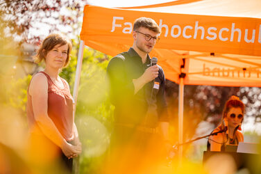 Promovierende sprechen bei sommerlichem Wetter auf der Bühne