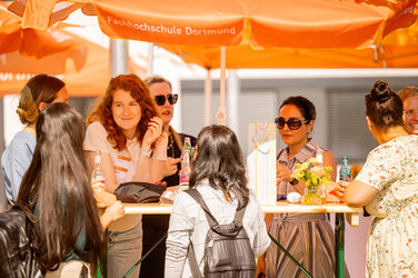 PhD students chat under a parasol in summer weather