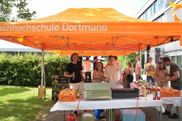 Unter orangefarbenen Pavillons versorgt die Fachschaft die Gäste mit Getränken.