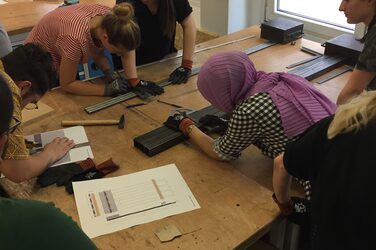 Students work together on their banisters on a workbench in the metal lab.