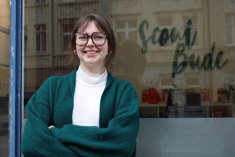 Porträtfoto von Hannah Sikau, die draußen vor dem Fenster der Hochschule vor Ort steht