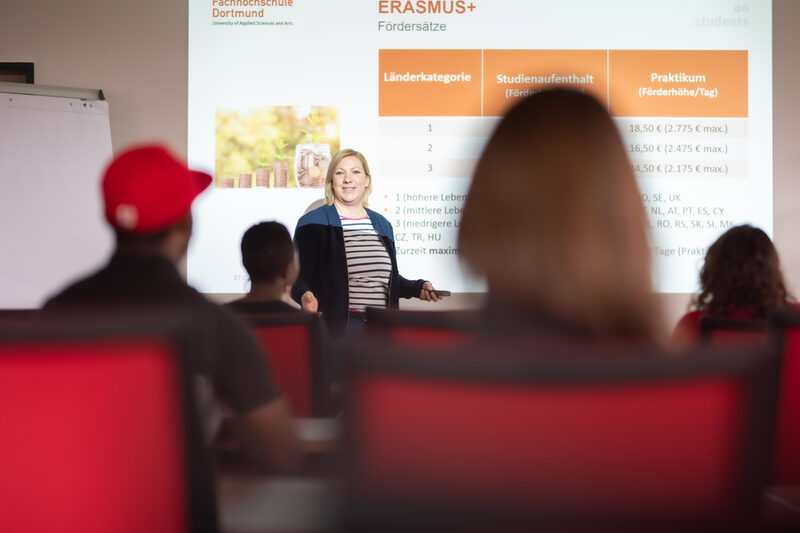 Foto von einer Infoveranstaltung des International Office in einem Hörsaal. Eine Dozentin steht vor einer projizierten Folie zum Thema "Erasmus".