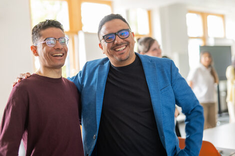 Two international students put their arms around each other, laughing.