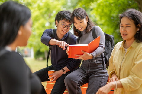 International students group around a bench on the outdoor area of the Emil-Figge-Straße campus and chat.