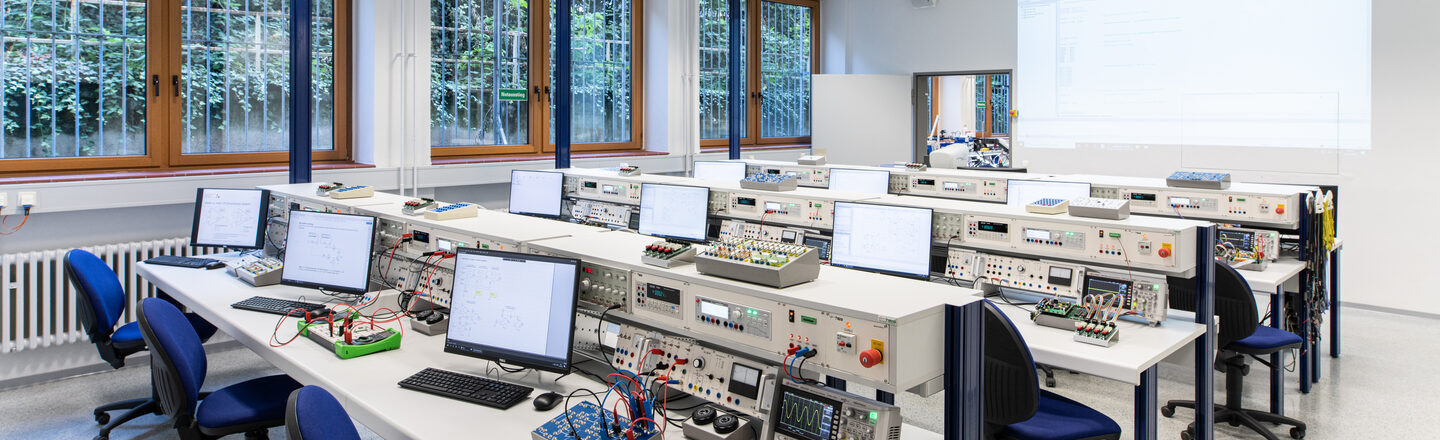 Photograph of the electronics and automation laboratory. Rows of tables with devices and computers.