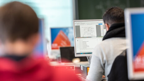 Photo of two students in rear view in PCs in a computer room.