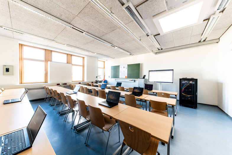 Foto eines mobilen Labors mit Laptops in einem Seminarraum. Vorne steht ein Monitor und ein Serverschank.