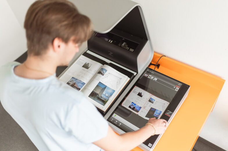 Photo of a student operating the book scanner in the library.