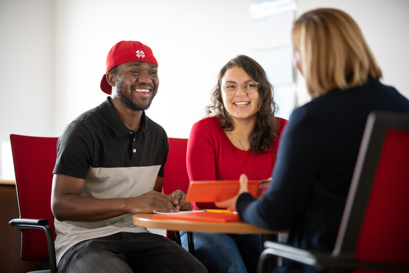 Foto von zwei internationale Studierende bei einem Beratungsgespräch mit einer Mitarbeiterin des International Office.