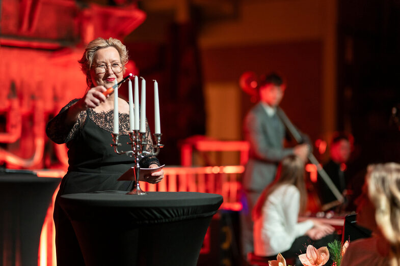 A person lights candles on a candlestick.