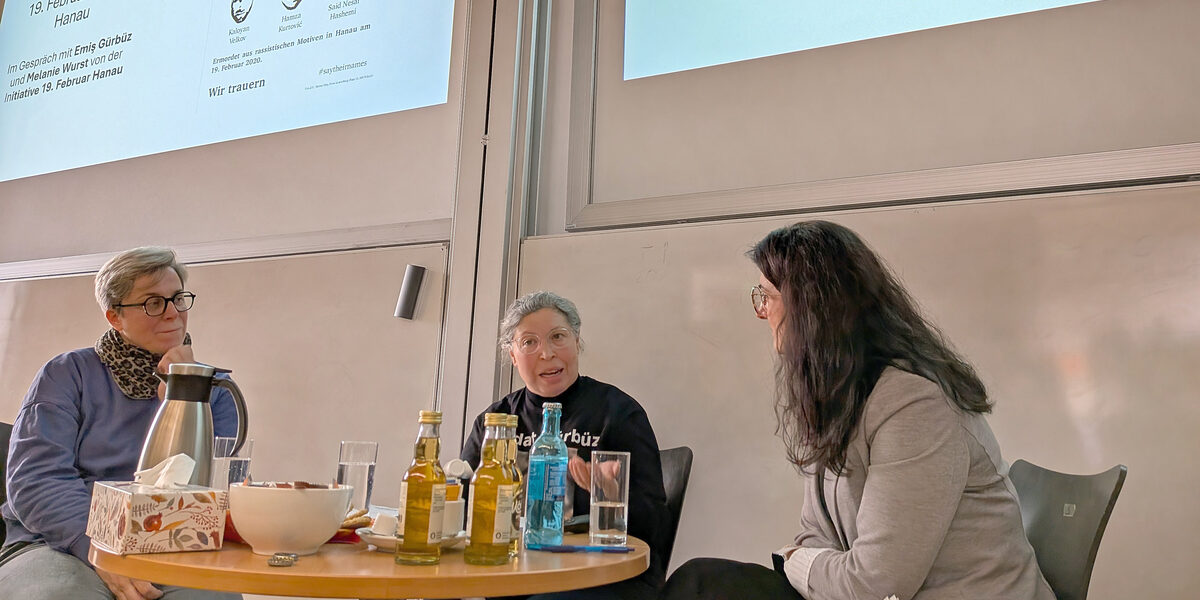 Menschen vor einer Leinwand in einem Hörsaal sprechen miteinander.