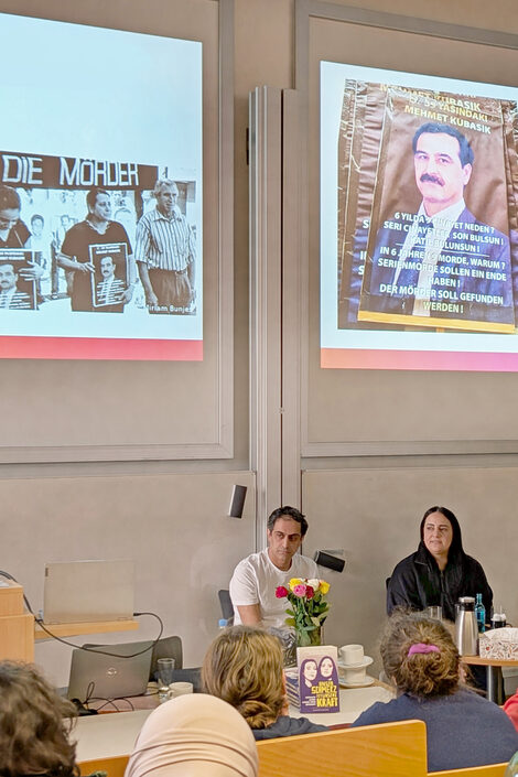 Menschen vor einer Leinwand in einem Hörsaal sprechen miteinander.