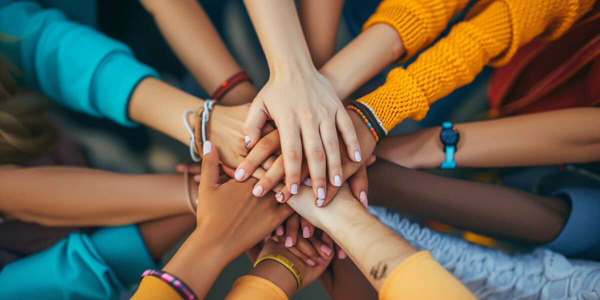 The hands of people of different skin colors touch each other.