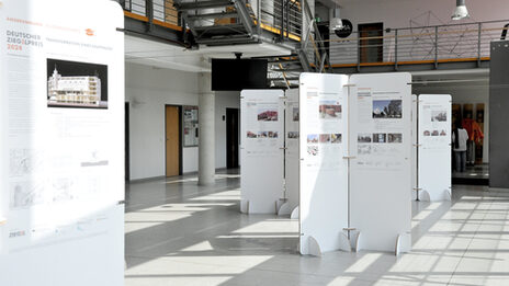 Exhibition in the foyer of the faculty with free-standing white panels presenting architectural projects for the German Brick Award 2024.