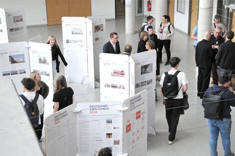 Ausstellung im Foyer des Fachbereichs mit freistehenden weißen Tafeln, auf denen Architekturprojekte zum Deutschen Ziegelpreis 2024 präsentiert werden.