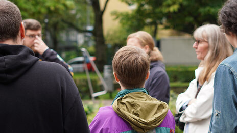 Sechs Personen stehen in einem Park.