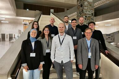 Einen Gruppe Menschen steht in einem Foyer auf einer Treppe.