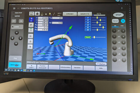 The control of a robot arm can be seen on a PC monitor.
