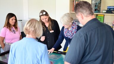 Mehrere Menschen stehen um einen Tisch herum, dessen Oberfläche ein Touchscreen ist.