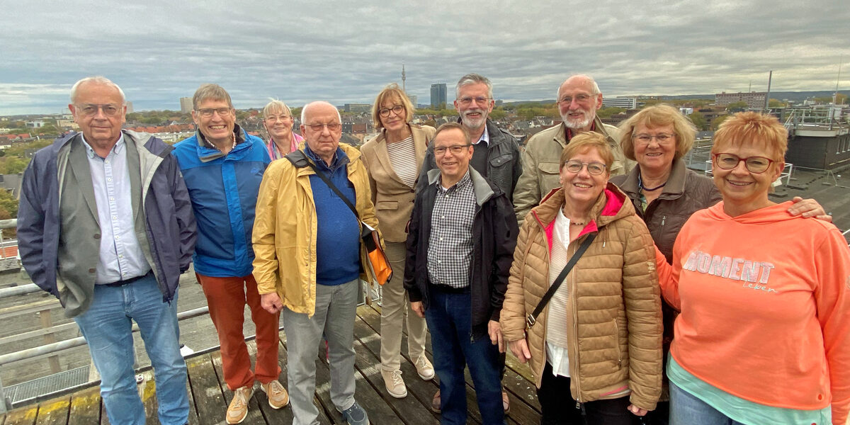 Eine Gruppe steht auf einer Plattform hoch über den Dächern der Stadt. Im Hintergrund sind die Hochhäuser von Dortmund zu sehen.