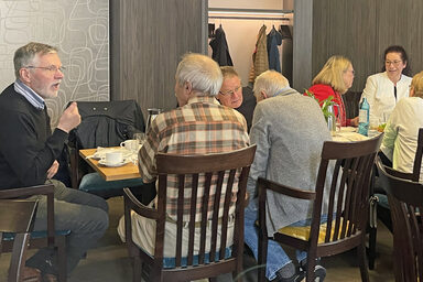 Menschen sitzen an Tischen und unterhalten sich.