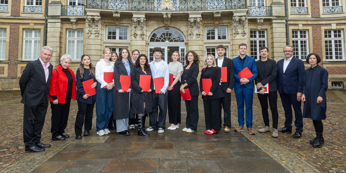 Gruppenfoto der Preisträger:innen des 13. Schlaun-Wettbewerbs 2024/25 vor dem Erbdrostenhof in Münster. Die Ausgezeichneten präsentieren ihre Urkunden gemeinsam mit Jury- und Forumsmitgliedern vor historischer Kulisse.