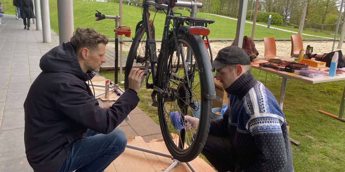 Zwei Personen schrauben am FH-Campus Emil-Figge-Straße an einem Fahrrad.