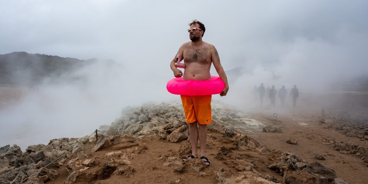 Auf dem Bild ist ein Mitglied des MSG-Kollektivs in einem natürlichen Pool in Island zu sehen. Das Bild ist inszeniert, u.a. mit einem rosa Schwimmreifen