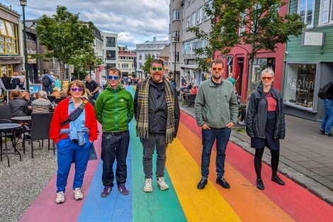 Gruppenbild des MSG Kollektivs auf der RAinbow Street in Reykjavik. Die Straße wird durch einen Regenbogen geziert.