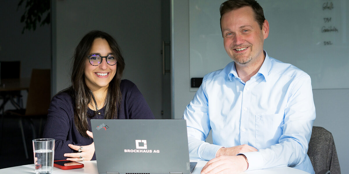 Two people are together in front of a monitor and analyze the data on the screen.