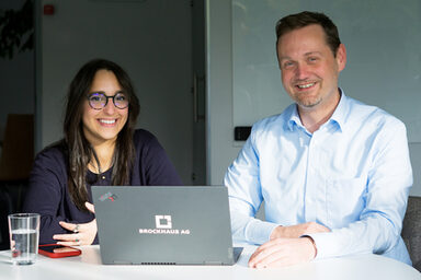 Two people are together in front of a monitor and analyze the data on the screen.