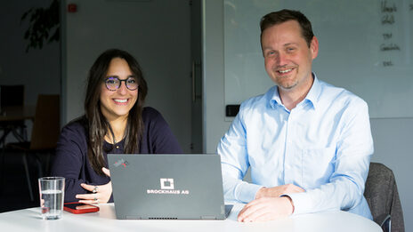 Two people are together in front of a monitor and analyze the data on the screen.