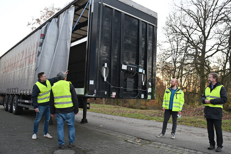 Vier Männer inspizieren einen LKW-Anhänger.