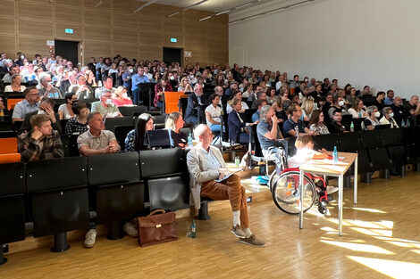 Menschen sitzen in einem Hörsaal und verfolgen einen Vortrag.