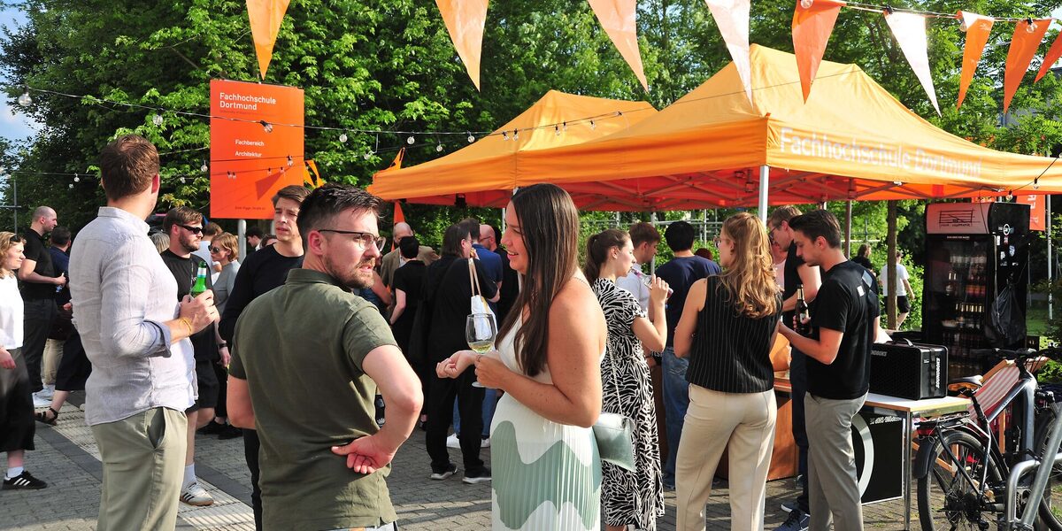 Menschen stehen auf dem Sommerfest des Fachbereichs Architektur der FH Dortmund. Unter orangefarbenen Pavillons versorgt die Fachschaft die Gäste mit Getränken.