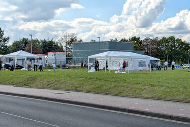 People set up pavilions and tents on a meadow.