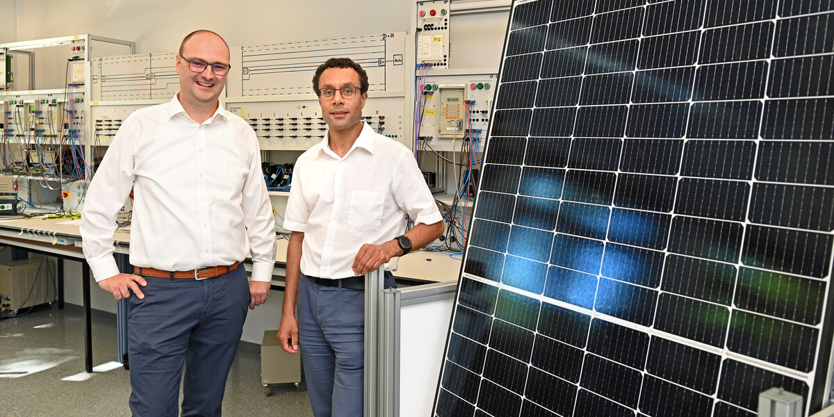 Two people stand next to a solar panel in a laboratory at Fachhochschule Dortmund.